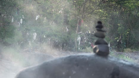 balanced stones with steam emanating from the thermal hot springs of rio caliente el salvador, wide rack focus shot