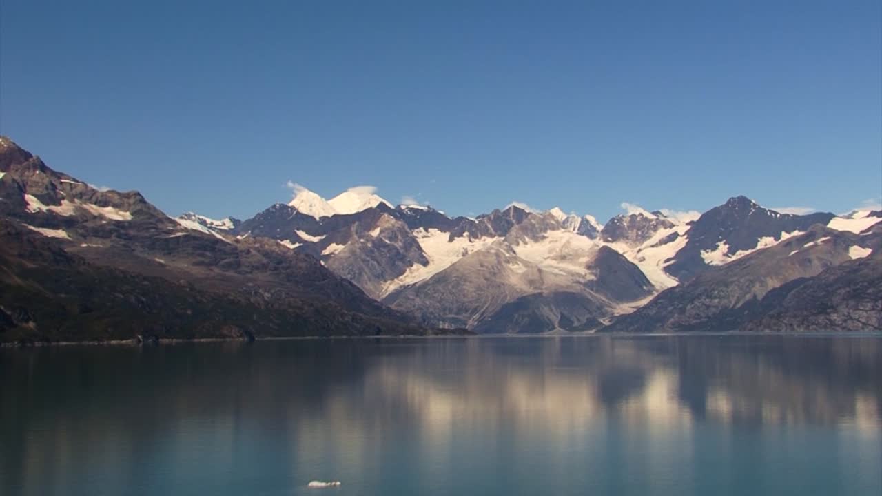백그라운드에서 눈 덮인 산, 알래스카에서 타르 입구의 잔잔한 물에서 순항