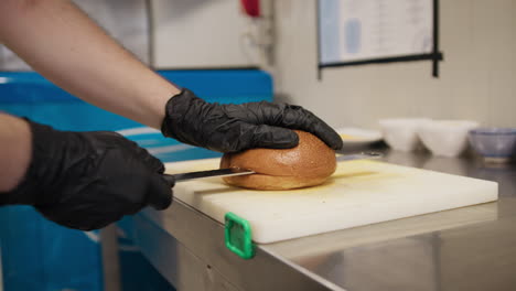 chef slicing in half a bun to start the preparation of the burger