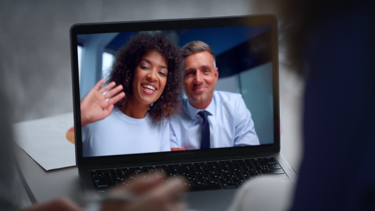 Smiling colleagues virtual conference by laptop webcam close up. Couple greeting
