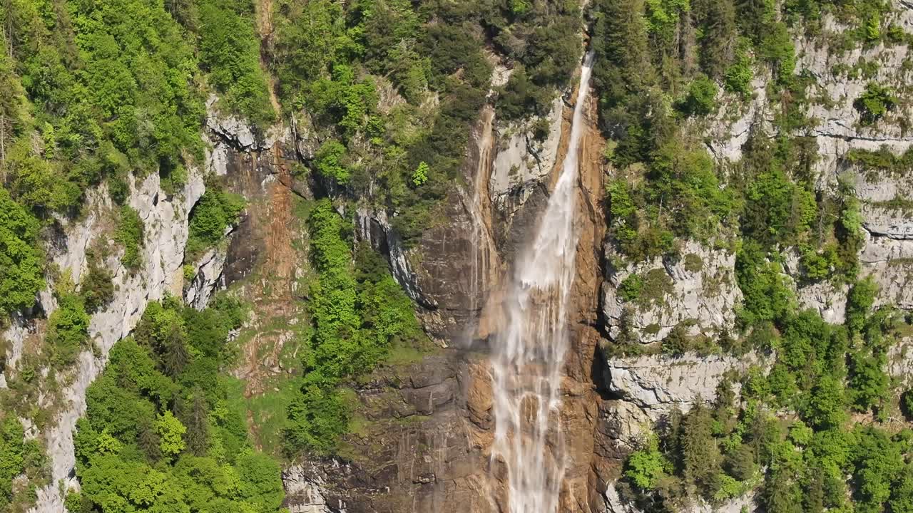 Close aerial view of Seerenbach Falls in Switzerland cascading down rugged cliffs, surrounded by lush greenery and dramatic rock formations, an awe-inspiring alpine natural wonder