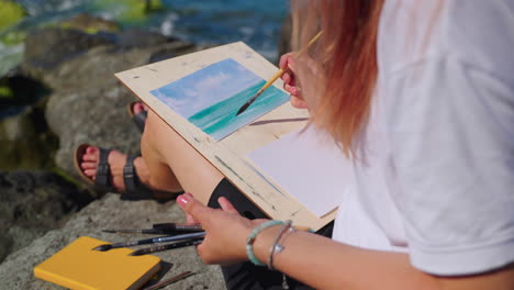 woman painting a seascape on the beach