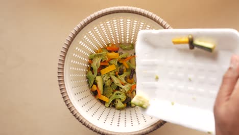 tirando verduras en un cubo de basura