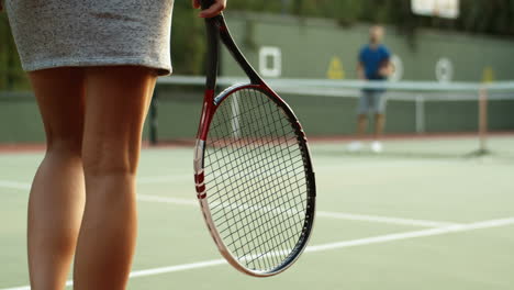 primer plano de una jugadora de tenis irreconocible caminando hacia la red y conociendo a un cojugador masculino