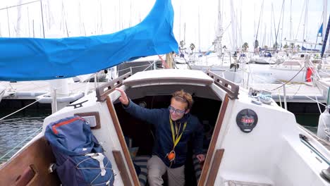 slow motion shot of a man heading onto the deck from a cabin below in a marina