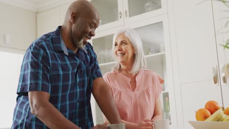 Happy-senior-diverse-couple-talking-in-kitchen