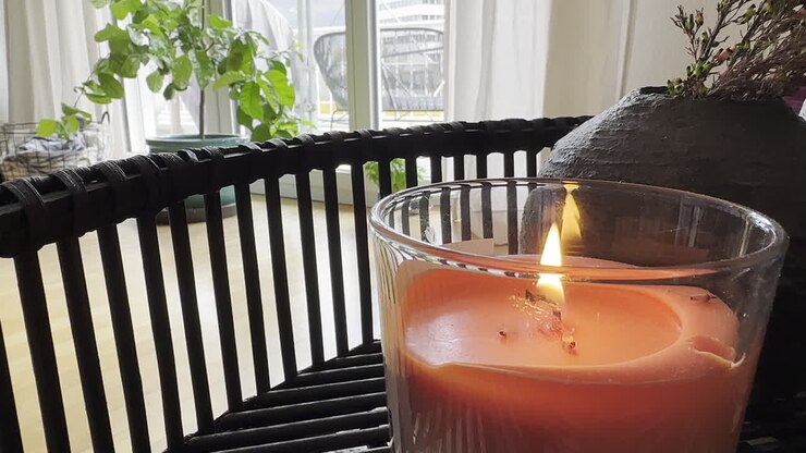 Nærbilde av et tent rødt stearinlys på et lite trebord