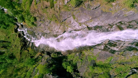 amazing slow motion aerial of a waterfall in green lush mountains in the soft dayligt