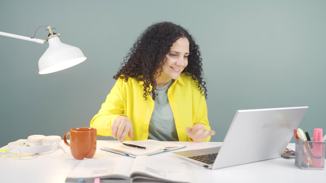 mujer joven trabajando en una computadora portátil con expresión feliz.