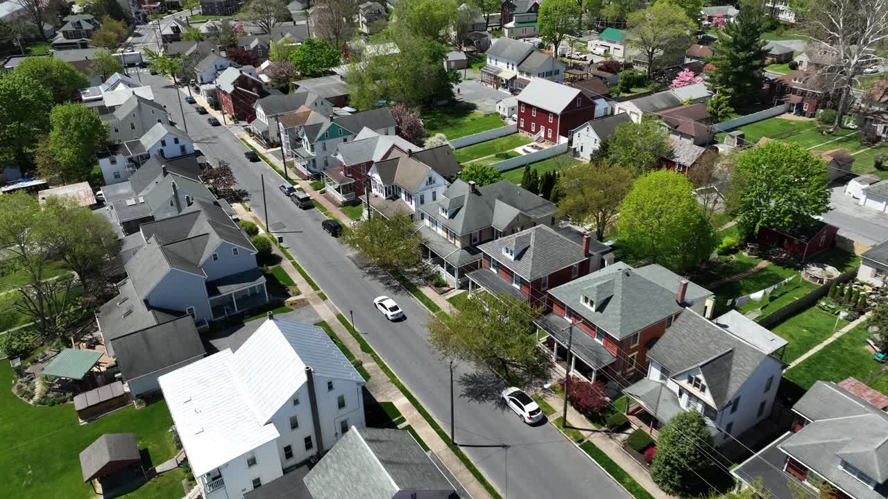 Ripresa aerea in movimento di un'auto bianca su strada in un pittoresco quartiere residenziale americano sotto la luce del sole