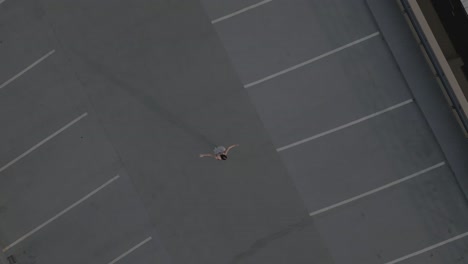 drone se aleja de una chica bailando sola en un parkade en la azotea