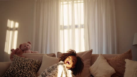 A child wrapped in a blanket, smiling and playing in a cozy living room