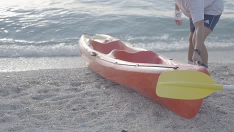 a man prepares a kayak for a ride near a beautiful beach