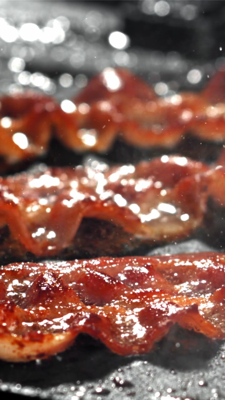 Strisce di pancetta sfrigolanti che friggono in una padella calda
