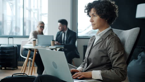 businesswoman working on laptop in airport lounge