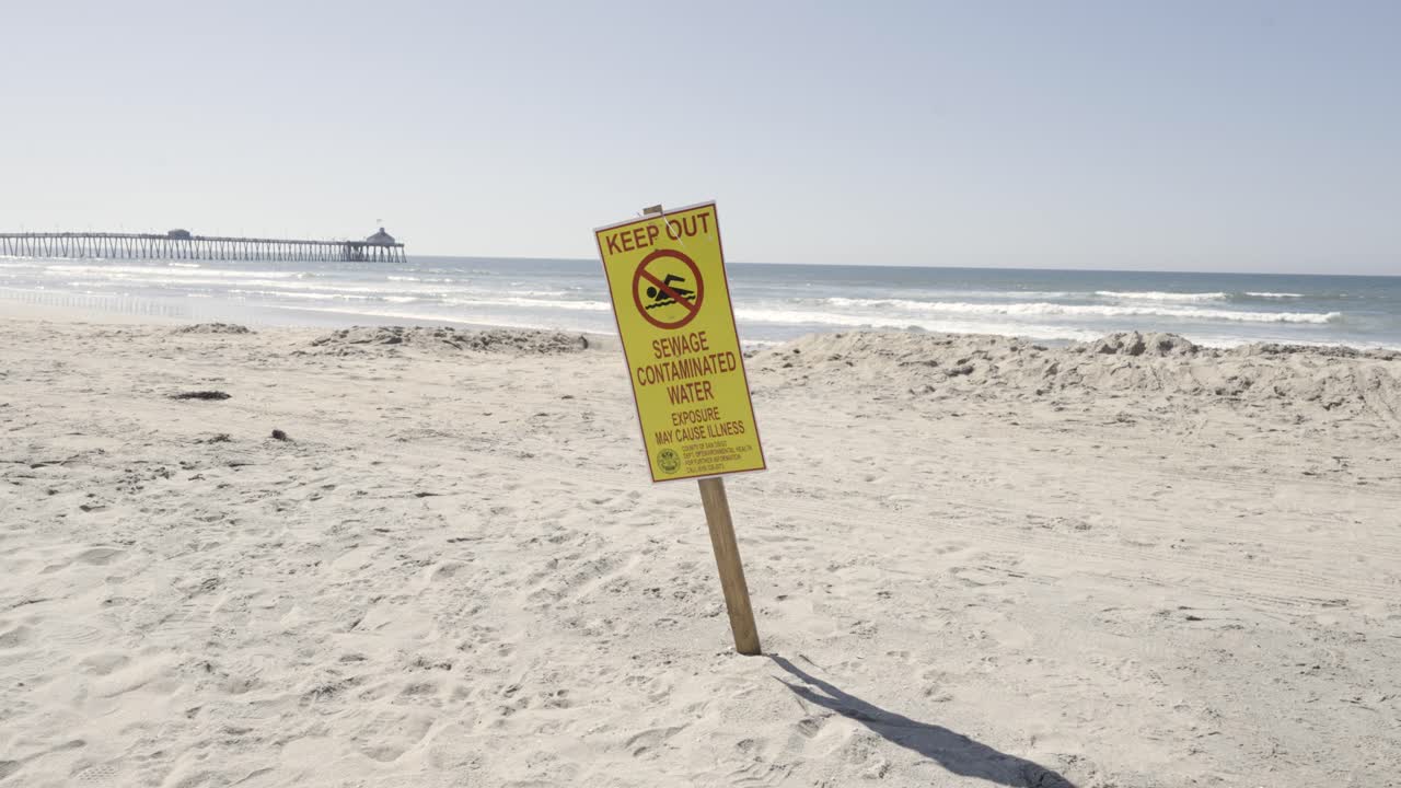manténgase alejado del agua contaminada con aguas residuales, tenga cuidado con el letrero en imperial beach, california, día soleado: cámara lenta con muelle