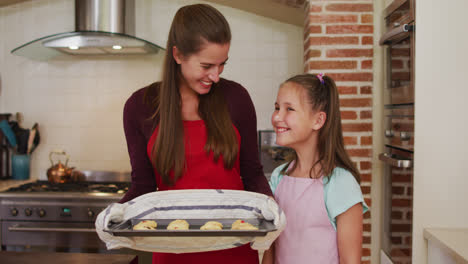 Portrait-of-caucasian-mother-and-daughter-standing-in-the-kitchen