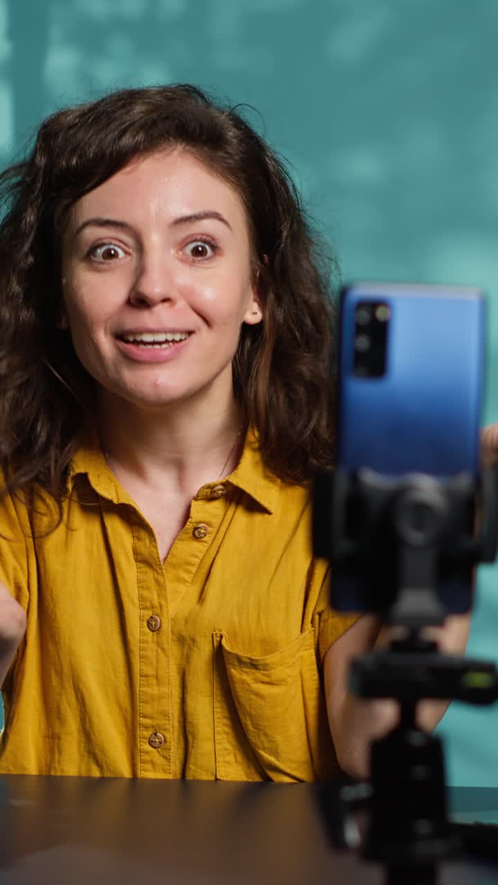 Ekspressiv kvindelig vlogger, der taler og gestikulerer til smartphone-kameraet
