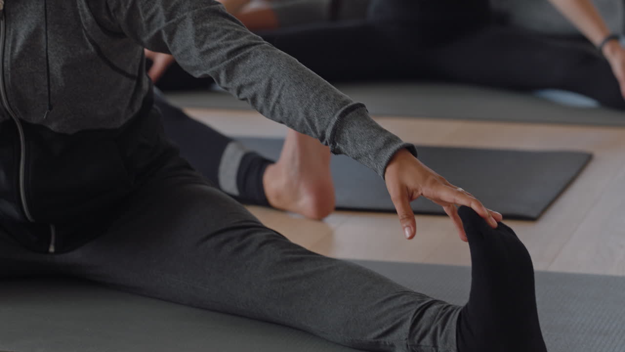 yoga class healthy group of women practice wide-angle seated forward bend pose enjoying fitness lifestyle exercising in workout studio