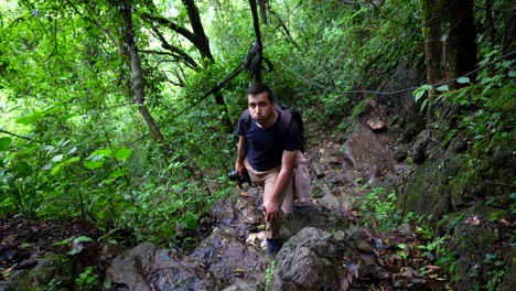 hombre cansado en una caminata empinada escalando difícil colina laozhai en la selva tropical