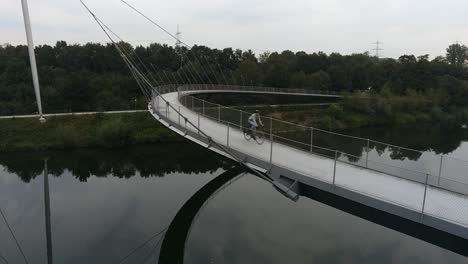 a person walking and cycling on a modern curved bridge over water