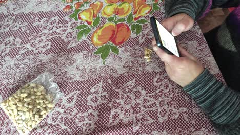 white woman eating peanuts on a table and using cell phone