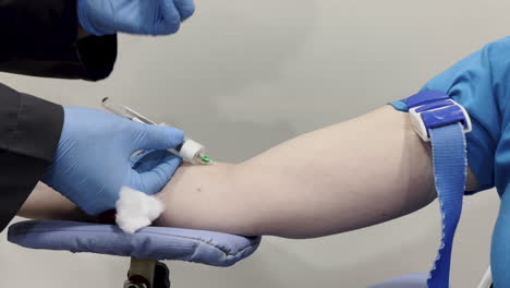 Close-shot-of-a-woman's-arm-and-a-nurse's-hands-changing-the-blood-test-collection-vial