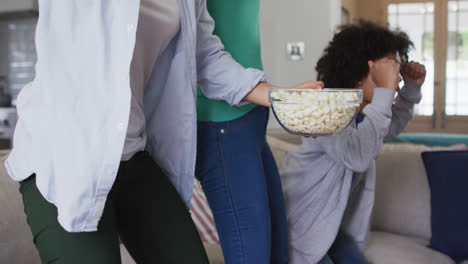 Mischlinge-Lesbisches-Paar-Und-Tochter-Vor-Dem-Fernseher-Essen-Popcorn