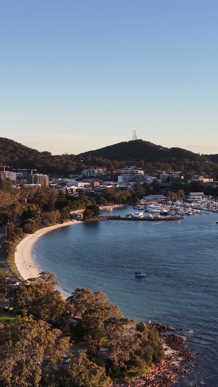 Panoramica aerea con drone sulla marina di Nelson Bay, spiaggia sabbiosa e colline boscose in Australia