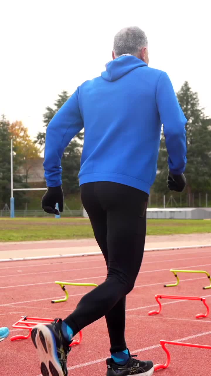 Senior Athletes Training with Hurdles on Running Track