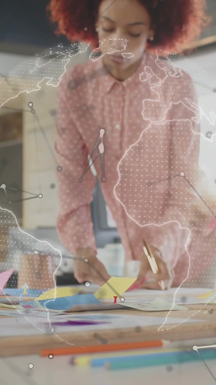 Vertical video: Designer sorting sticky notes, planning as globe rotating and team handing sheets