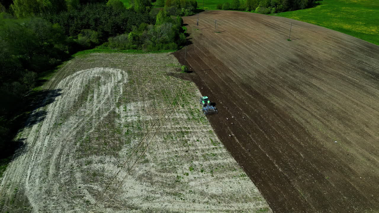 tractor verde con arado arados pistas en el campo, órbita aérea día soleado