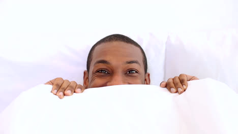 handsome man peeking up from under the covers