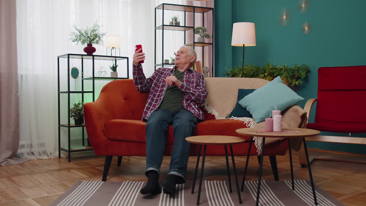 abuelo mayor feliz sosteniendo teléfono inteligente viendo video móvil llamando en línea haciendo selfie en casa