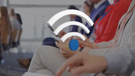 animation of wifi icons over diverse business people using electronic devices