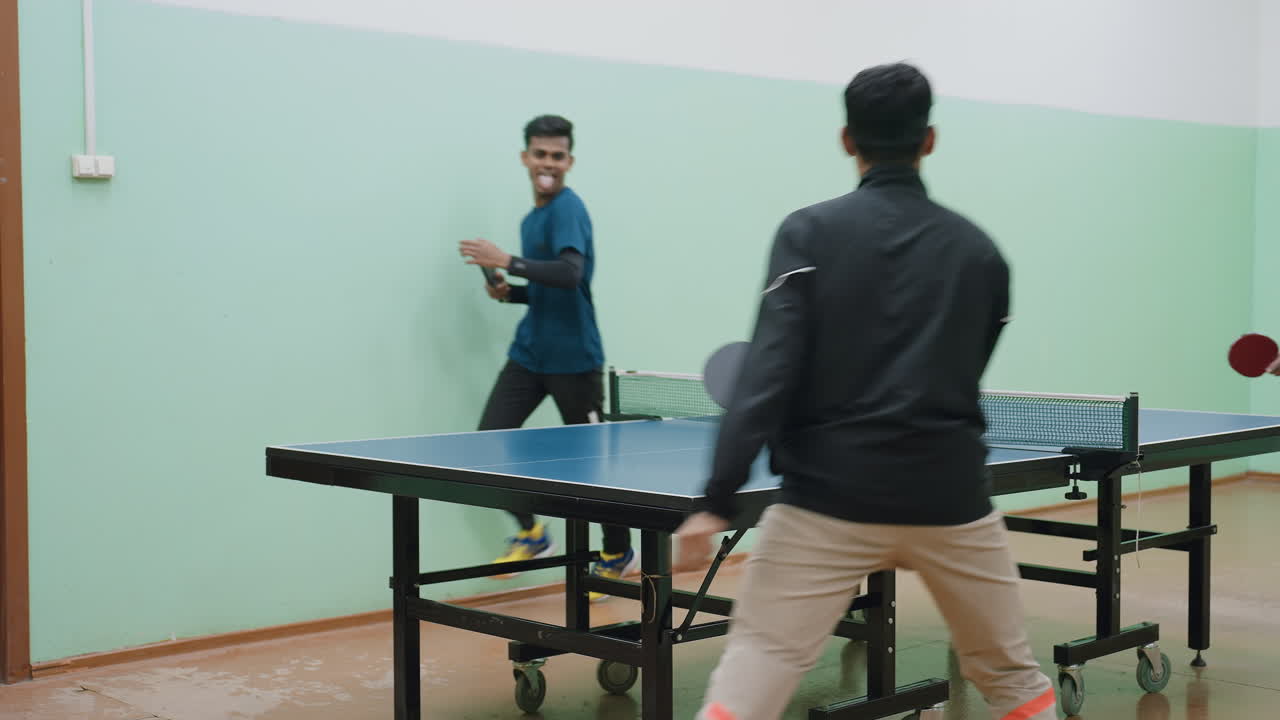 Group of athletes engage in lively indoor table tennis match, turning around table with quick movements, hitting ball energetically while enjoying teamwork