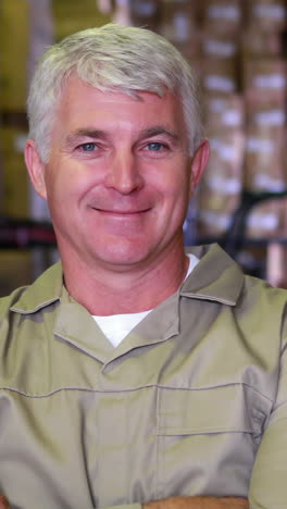 warehouse worker smiling at camera with arms crossed