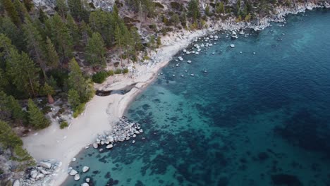 Toma-De-Drones-De-La-Playa-Chimney-Y-El-Agua-Azul-Cristalina-Del-Lago-Tahoe-Durante-La-Puesta-De-Sol