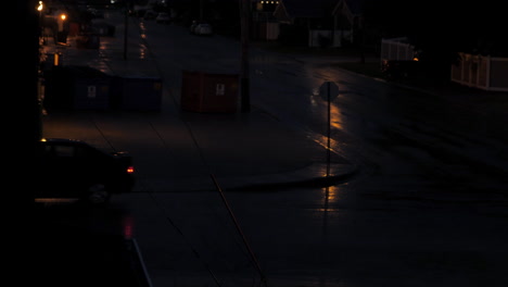 car turning at corner of wet street in rain at night
