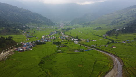 establecimiento aéreo de la mierda de la región rural en pokhara con pequeños pueblos y campos agrícolas tropicales entre las montañas durante el día de niebla