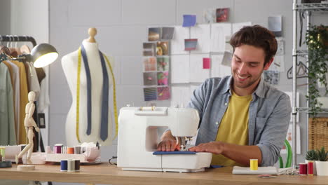 Male-Student-Or-Business-Owner-Working-In-Fashion-Industry-Using-Sewing-Machine-In-Studio