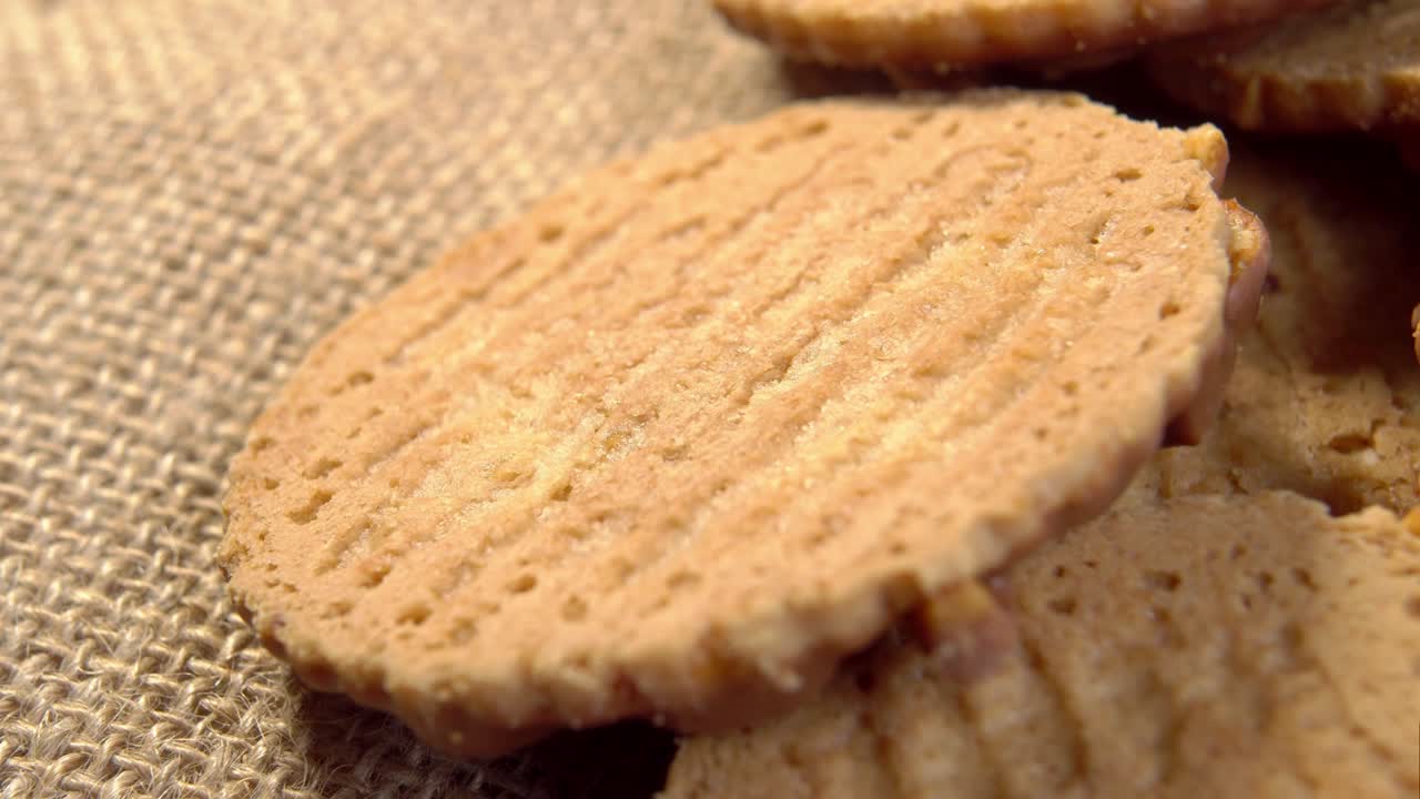 Texture of baked crispy biscuit close-up. Textured fiber cookie on rustic burlap cloth
