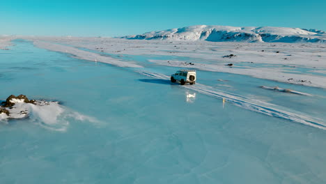 side profile aerial of white defender jeep traveling down arctic landscape in winter in iceland