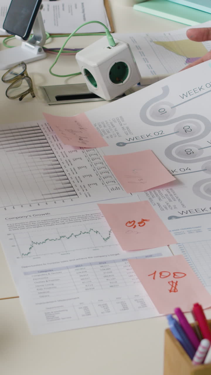Hands working on business documents and charts at an office desk