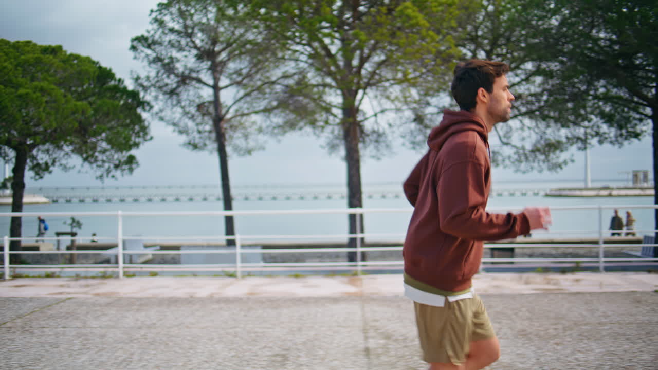 Fit jogger running bay in morning. Sporty man jumping warming up before training