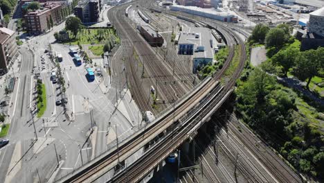 trem viajando e transportando em trilhos de trem europeus sob a ponte da ferrovia vazia no centro urbano da cidade por edifícios comunitários residenciais e vizinhança, aérea aérea para trás