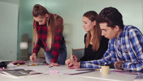 Group-of-young-creative-people-working-together-in-modern-office.-Young-professionals-making-sketches-sitting-at-the-table,-preparing-their-new-project-and-drinking-coffee-in-slowmotion