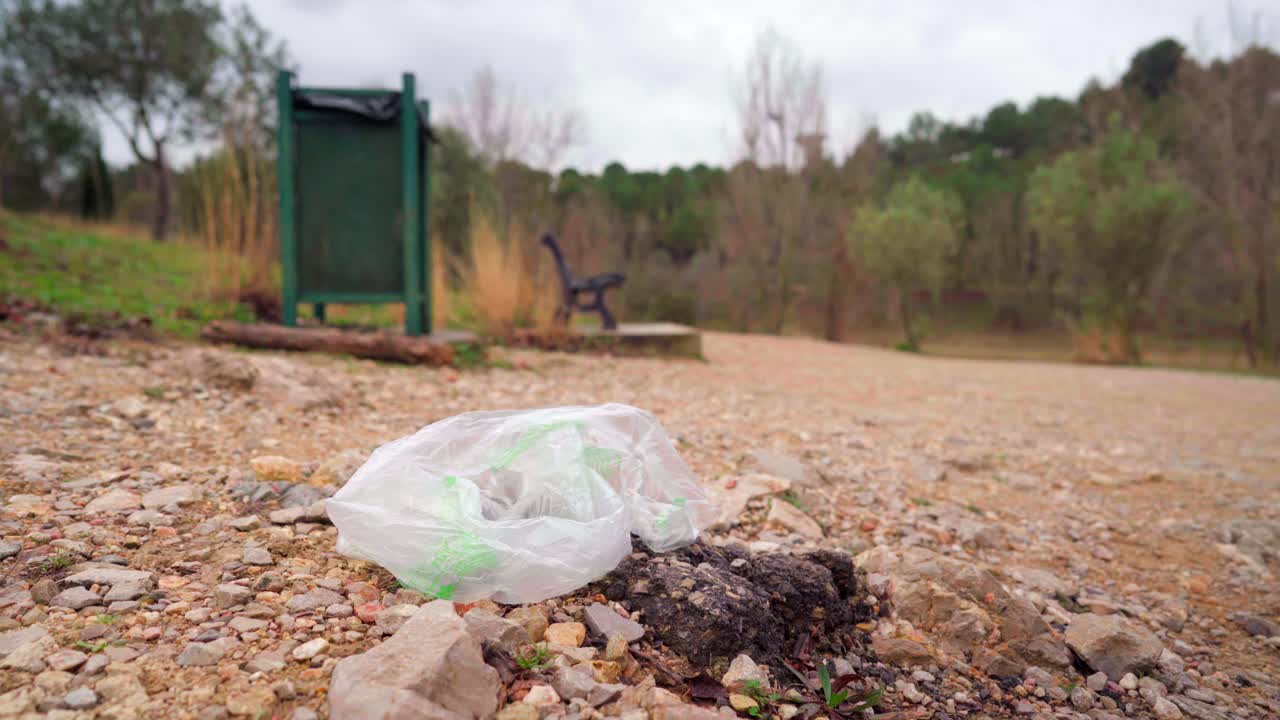 bolsa de plástico desechada en el parque nacional junto a un basurero, contaminación y basura en la naturaleza
