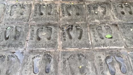 Point-of-view-of-feet-prints-on-the-pathway-in-Wat-Samphran-Temple-in-Nakhon-Pathom-province,-West-of-Bangkok,-Thailand