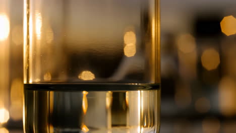 abstract close-up of liquid in glass beaker with golden bokeh